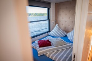 Een gezellig vakantiehuisje met uitzicht op een meer, een gestuufd hoofdeinde en gestreept beddengoed.