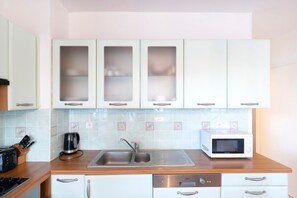 Una cocina con armarios blancos, un fregadero, un microondas y una cafetera.