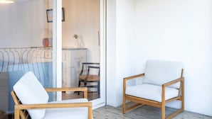 Ein Zimmer mit einem Holzstuhl, einem weißen Sofa und einer Glastür, die in einen anderen Raum führt.