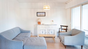 Ein modernes Wohnzimmer mit einer Couch, einem Sessel, einem Holztisch und einer Pendelleuchte.