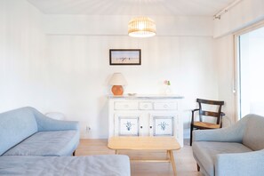 Une pièce comprenant un canapé, une table en bois, une lampe, une chaise et un meuble contenant des objets décoratifs.