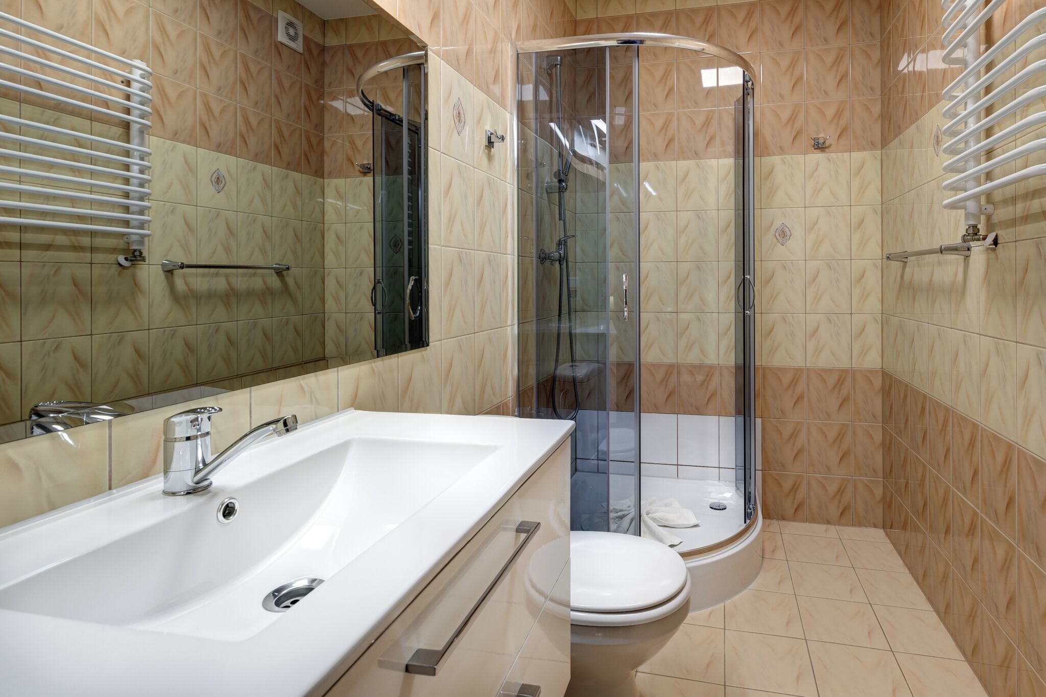 A bathroom with a white bathtub, a toilet, and a glass-enclosed shower.