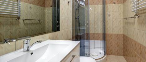 A bathroom with a white bathtub, a toilet, and a glass-enclosed shower.