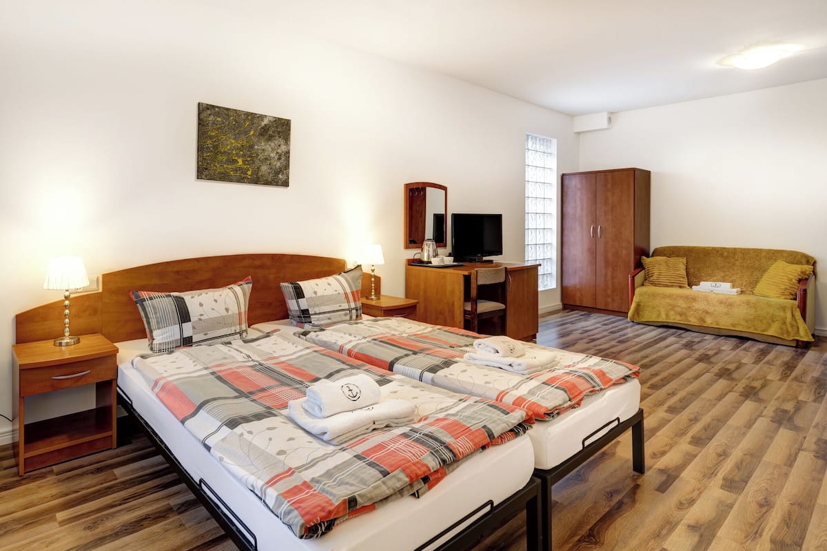 Un dormitorio con cama doble, televisión, armario y sofá.