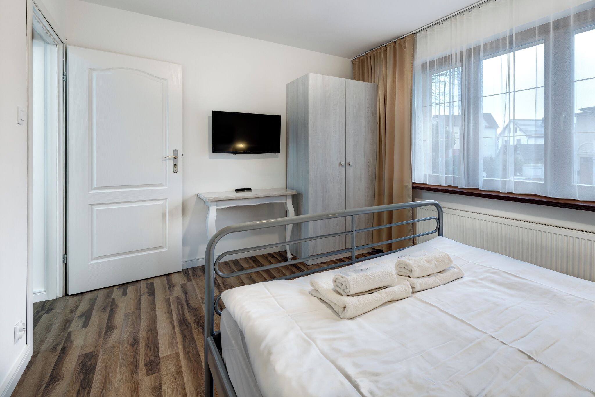 Hotellihuone, jossa on sänky, työpöytä, televisio ja vaatekaappi.