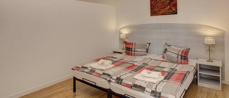 A bedroom with a bed, two bedside tables, a nightstand, and a painting on the wall.