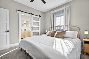 Une chambre à coucher avec un grand lit, des lampes de chevet, une armoire et une porte coulissante donnant sur une salle de bain.