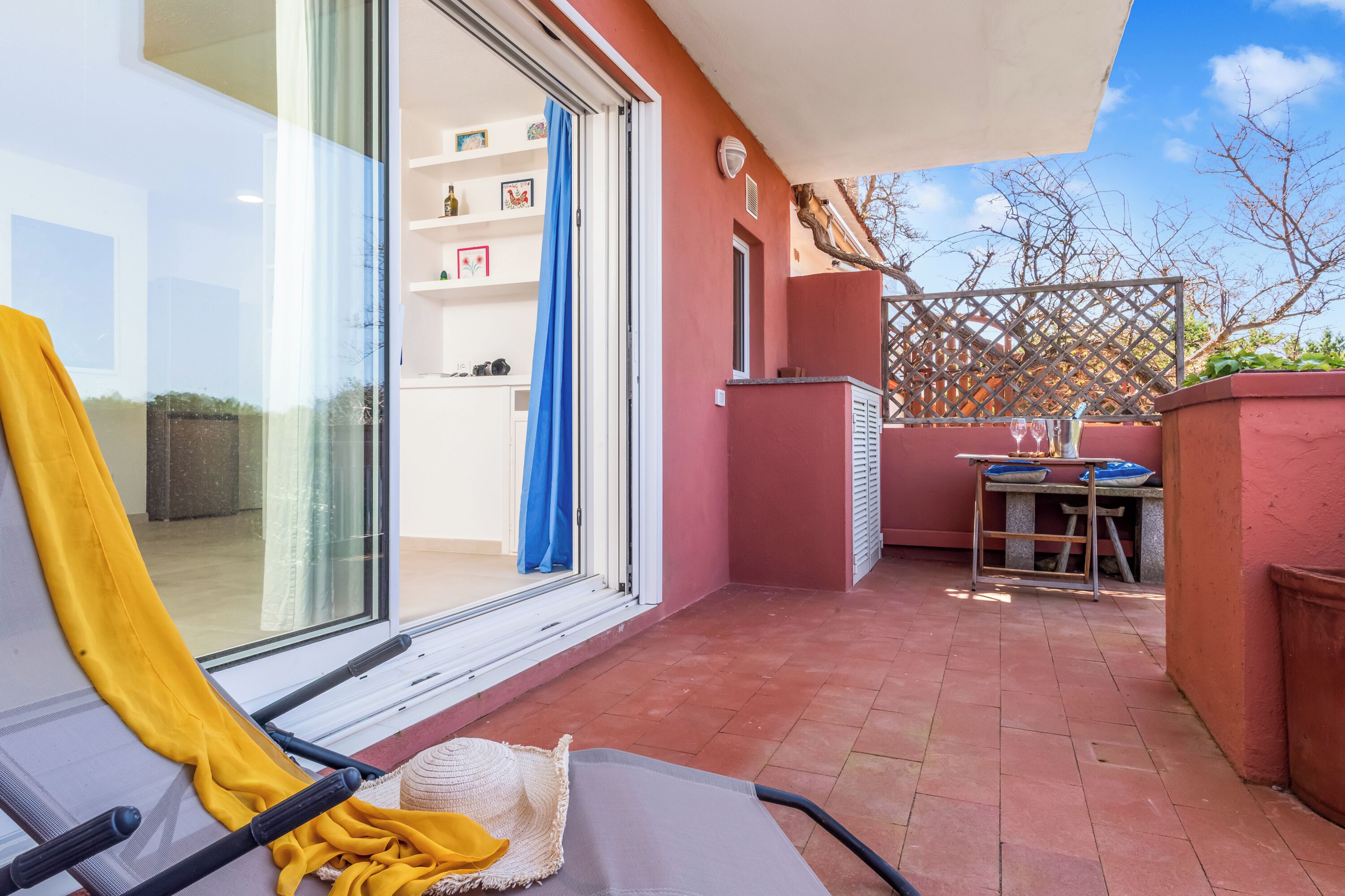 A balcony with a chair, a table, and a blue curtain.