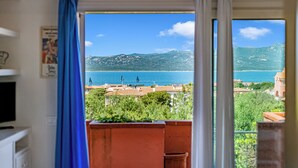 A room with a view of a coastal area, a window with a curtain, and a potted plant. - Aironi 34 (Olbia)