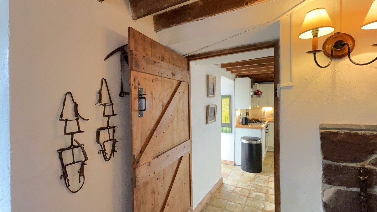 A rustic interior with a wooden door, wall-mounted lights, and a stone fireplace.