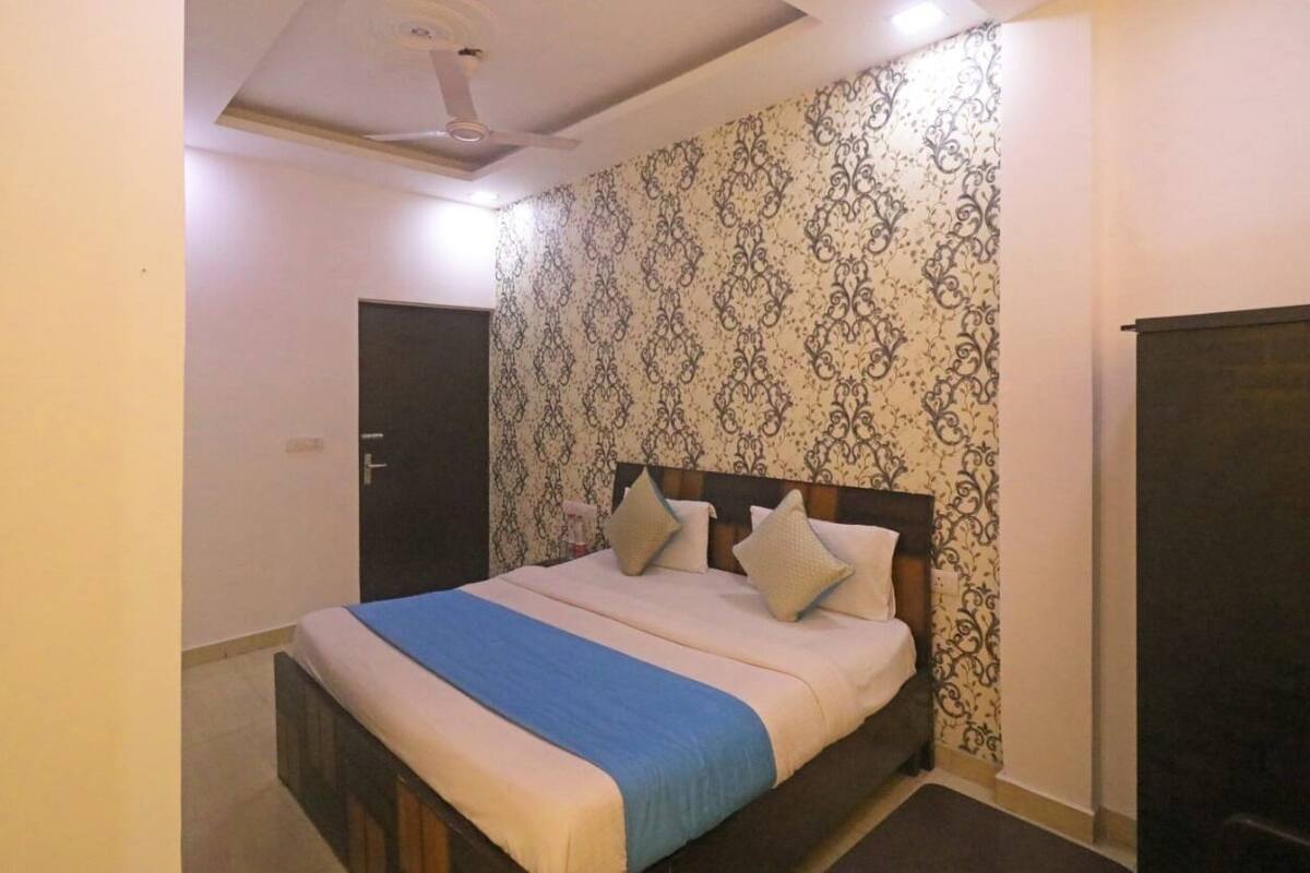 A bedroom with a bed, a door, and a patterned wallpaper.