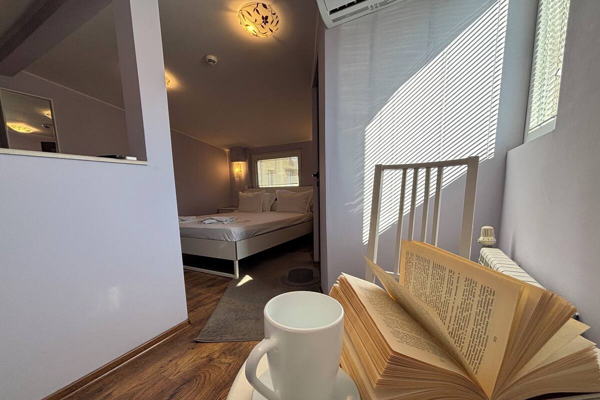 A cozy bedroom with a bed, bedside table, and a cup of coffee on a saucer.