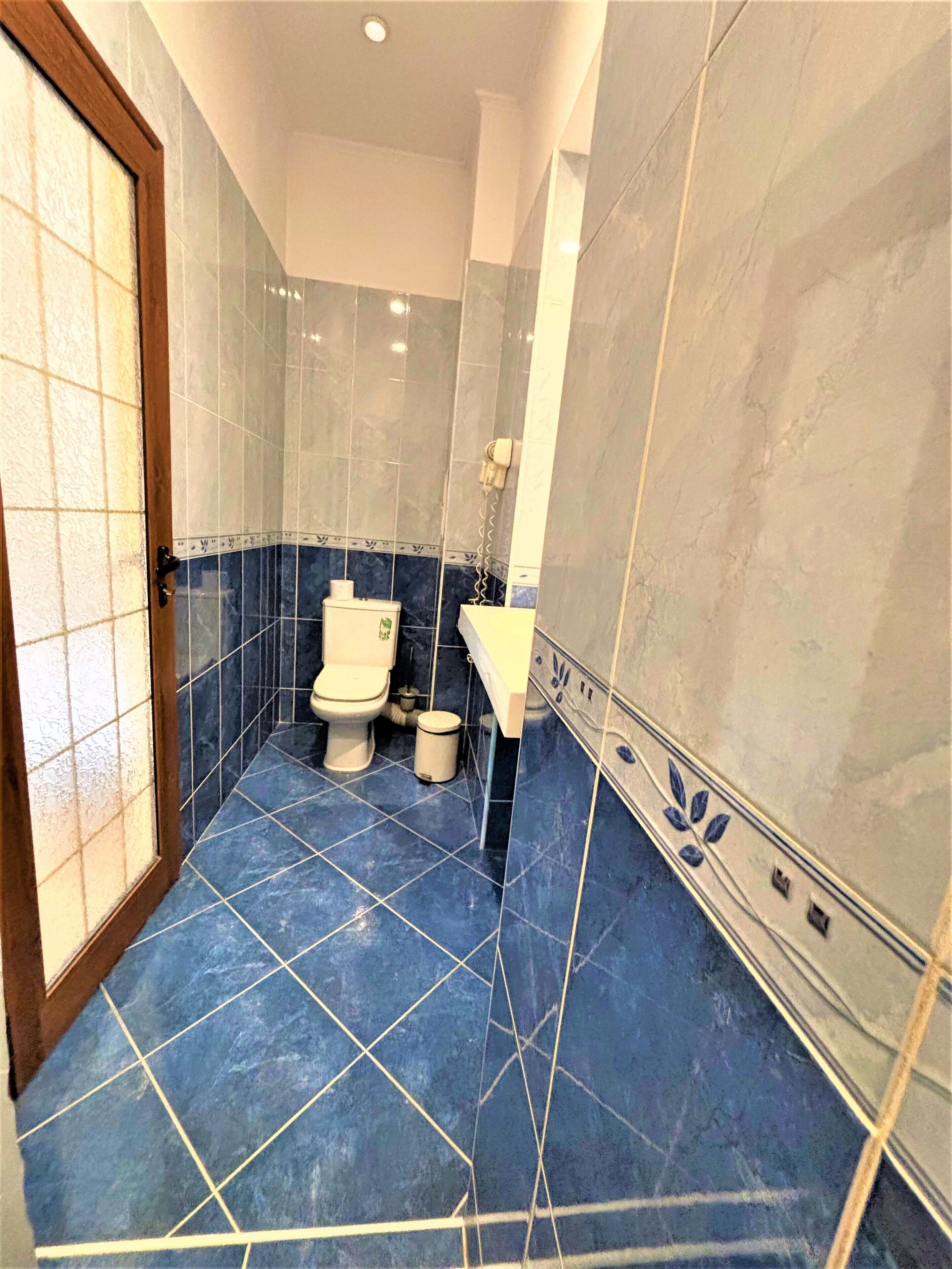A bathroom with a toilet, sink, and blue tiled floor.