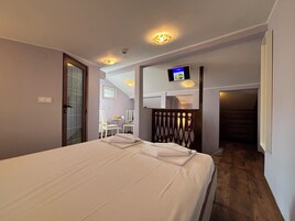 A hotel room with a bed, a TV mounted on the wall, and a small table with chairs.