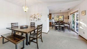 Un coin repas avec une table et des chaises en bois, un lustre et un tableau au mur.