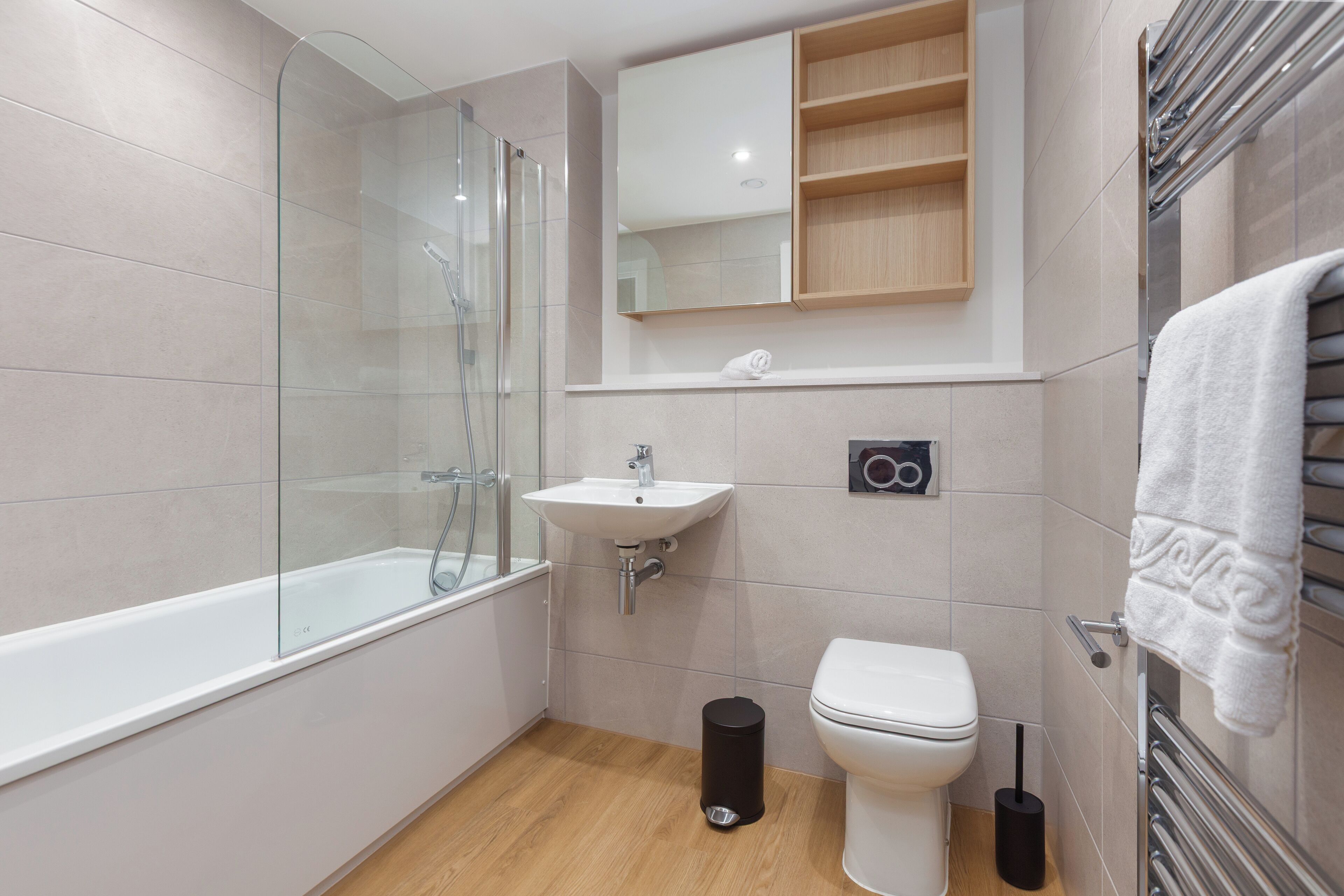 Une salle de bain moderne avec une douche à parois de verre, un lavabo blanc, des toilettes et un porte-serviettes.