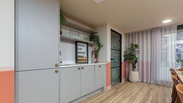 A modern kitchen with grey cabinets, a wooden countertop, and a sign that reads "WORK EAT DRINK".