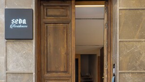 A wooden door with a sign for 'Seda Residences' above it, leading to a staircase with a patterned rug.