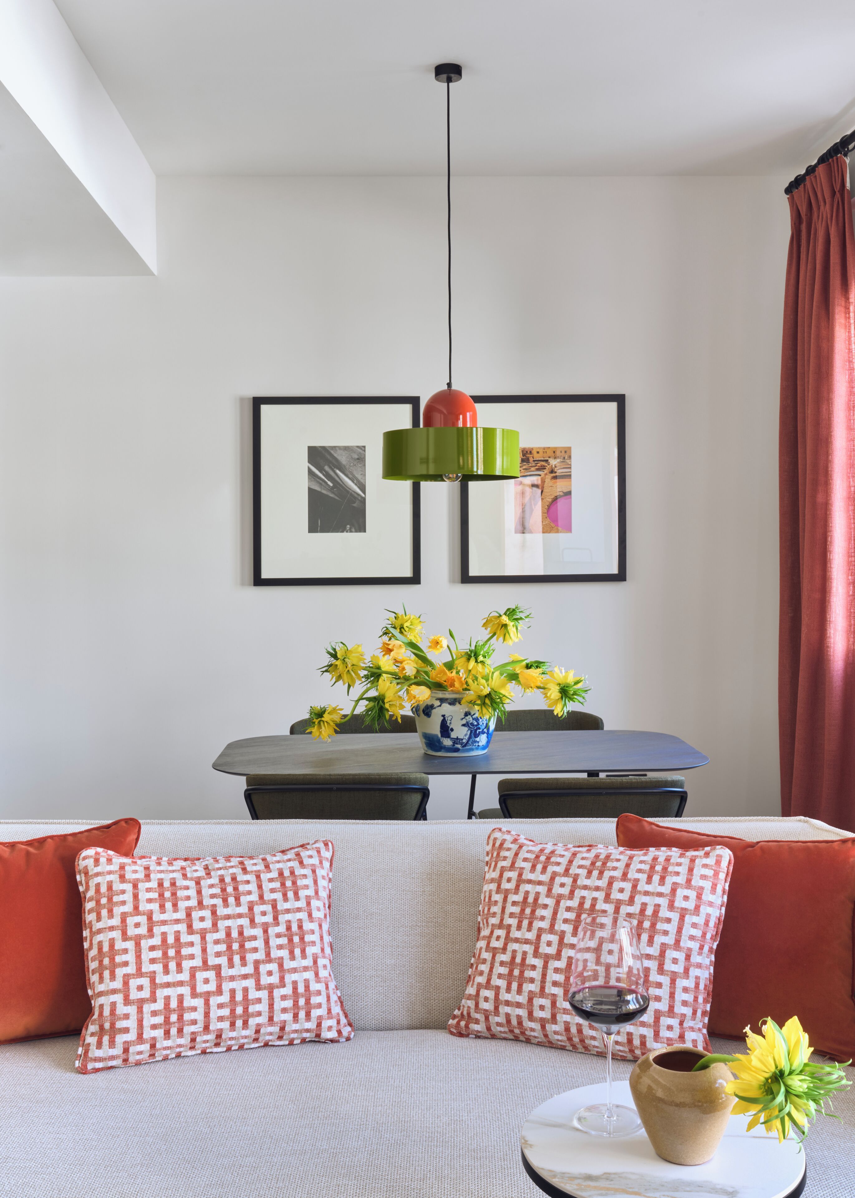 Una sala moderna con un sofá, una mesa de comedor y una lámpara colgante.