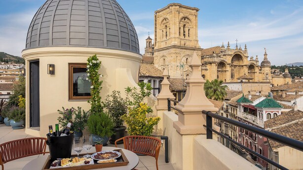 A terrace with a table set for dining, a decorative dome, and a historic building in the background.