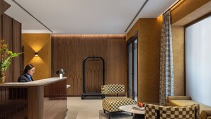 A hotel lobby with a reception desk, checkered chairs, a small table, and a large window.
