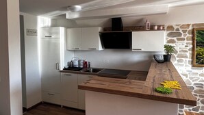 A modern kitchen with white cabinets, a built-in stove, and a stone accent wall.