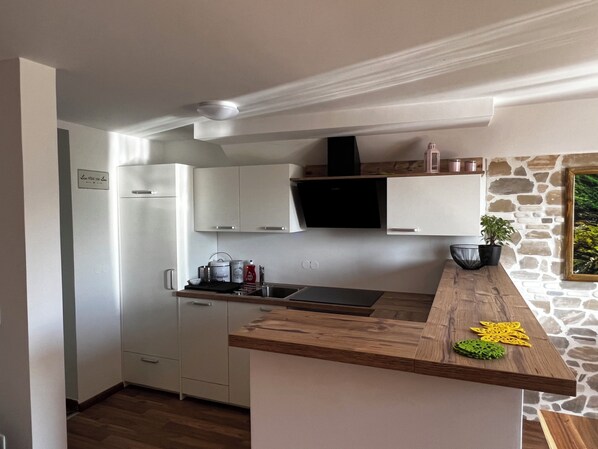 Una cocina moderna con armarios blancos, estufa integrada y una pared decorativa de piedra.