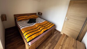 A single bed with a striped bedspread, a wooden headboard, and a wooden wardrobe.