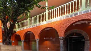 A courtyard with a brick archway, a tree, and a balcony with a railing. -  Casa Terra Cusco (Cusco)
