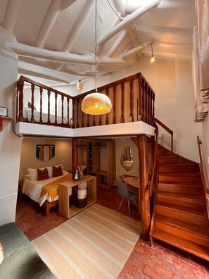 Camera in stile loft con scala in legno, soppalco e lampadario.