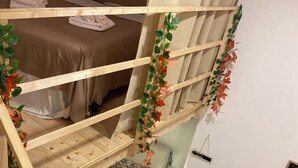 A dorm-style room with bunk beds, a small table with a plant, and a wall-mounted TV. - Vacation home Queen Matthias (Napoli)