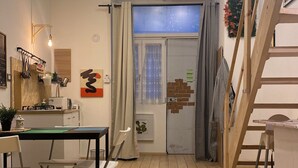 A cozy room with a wooden floor, a dining table with chairs, a staircase, and a door leading to another room. - Vacation home Queen Matthias (Napoli)