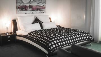 Un dormitorio moderno con una cama curvada, una mesita de noche con una lámpara y un cuadro de un coche en la pared.