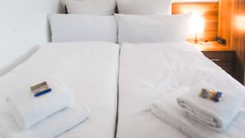A double bed with white linens and two towels on each side.