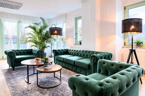 A modern living room with a green sofa set, a coffee table, and a floor lamp.