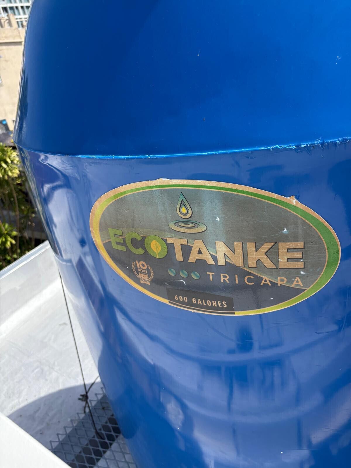 A blue barrel with a label that reads 'ECOTANKE TRICAPA' and '600 GALONES'.