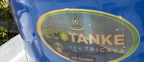 A blue barrel with a label that reads 'ECOTANKE TRICAPA' and '600 GALONES'.