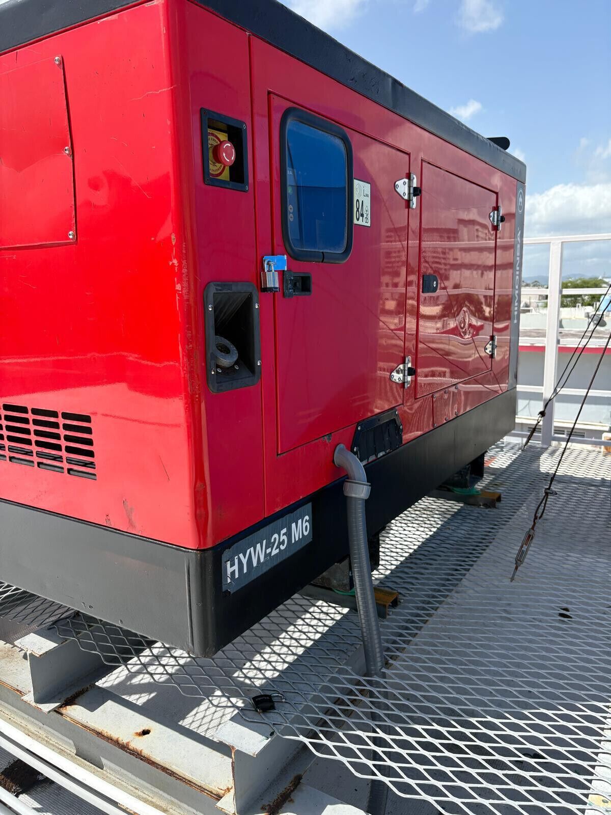 A red industrial machine with a label 'HYW-25 M6' on the side, a blue window, and a metal grate on the floor.