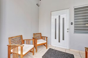 A room with a white door, two wooden chairs with cushions, and a small rug on the floor. - Beautiful 2 Bedroom in Miramar! (San Juan)