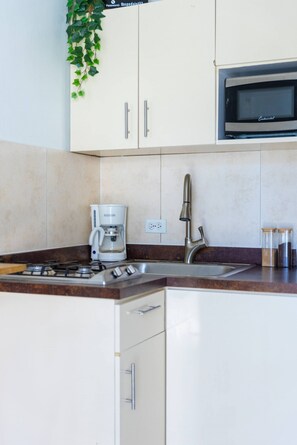A kitchen with a coffee maker, a microwave, and a sink. - Beautiful 2 Bedroom in Miramar! (San Juan)
