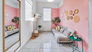 Ein modernes Wohnzimmer mit einer Couch, einem Couchtisch und einem Beistelltisch. Ein großes Spiegel, eine Stehlampe und ein Gemälde sind an der Wand zu sehen.