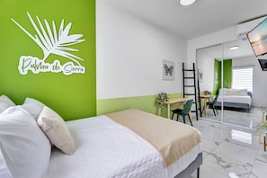 A hotel room with a bed, a desk, and a chair. There is a mirror on the wall and a plant on the desk. - Centric, Spacious, Stylish Miramar Unit, Sleeps 4 (San Juan)