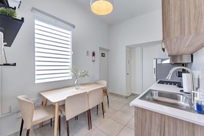 A modern kitchen with a dining area, including a table with chairs, a built-in oven, and a sink. - Centric, Spacious, Stylish Miramar Unit, Sleeps 4 (San Juan)