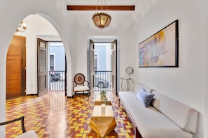 A spacious living area with a patterned floor, a sofa, a coffee table, a chair, and a hanging light fixture. - Old San Juan 3BR • Patio • Sleeps 6 (San Juan)
