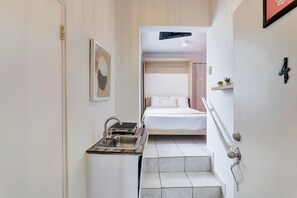 A compact hotel room with a kitchenette, a bed, and a small bathroom. - Bright, Centric and Cozy Studio In The Heart of Miramar (San Juan)