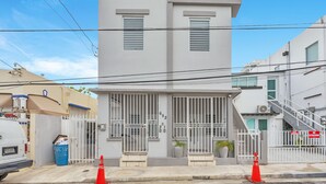 Un edificio moderno de dos pisos con entrada protegida por un portón, el número '652' visible en la puerta y una escalera a la derecha.