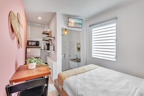 Ein gemütliches Schlafzimmer mit einem Bett, einem Schreibtisch mit Stuhl, einer Mikrowelle und einem Kühlschrank.