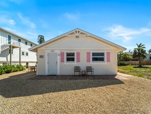 A single-story building with a white exterior, a front door, and two windows with shutters. - Seahorse Cottage 1 | Coastal Hideaway with Private Beach (Englewood)