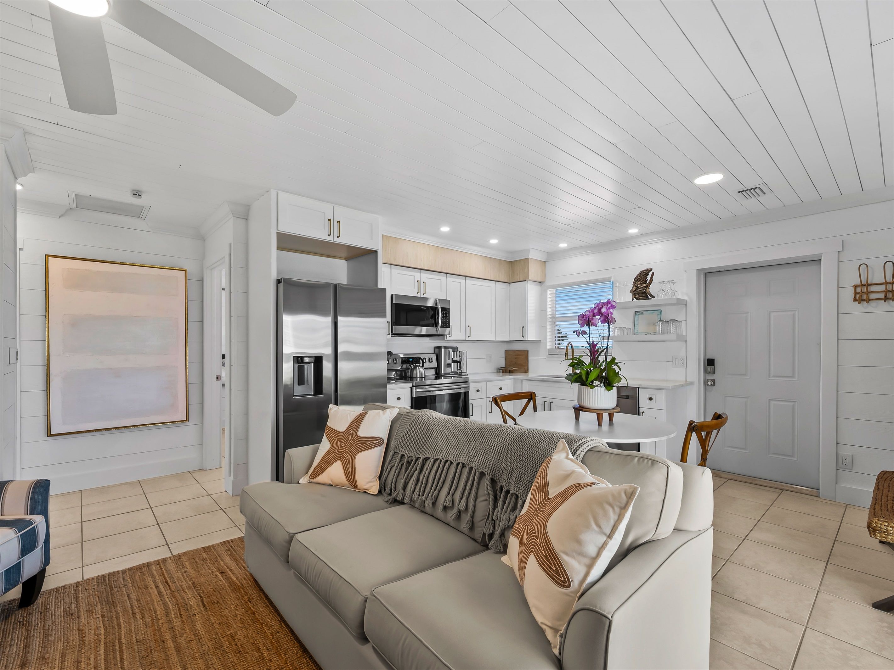 A modern living room with a sofa, a dining table, and a kitchen area with appliances.