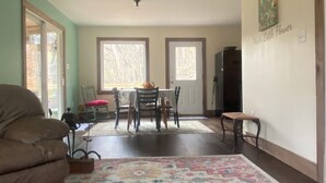 Un salón amplio con ventilador de techo, un tapete grande y colorido, y un comedor con mesa y sillas.